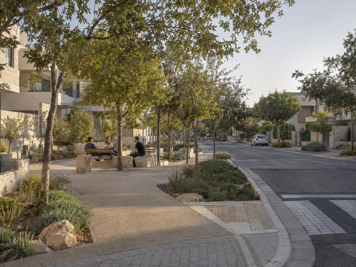 הרחבה יישובית עם מדרכות מוצלות, צמחייה ומקום מפגש קהילתי